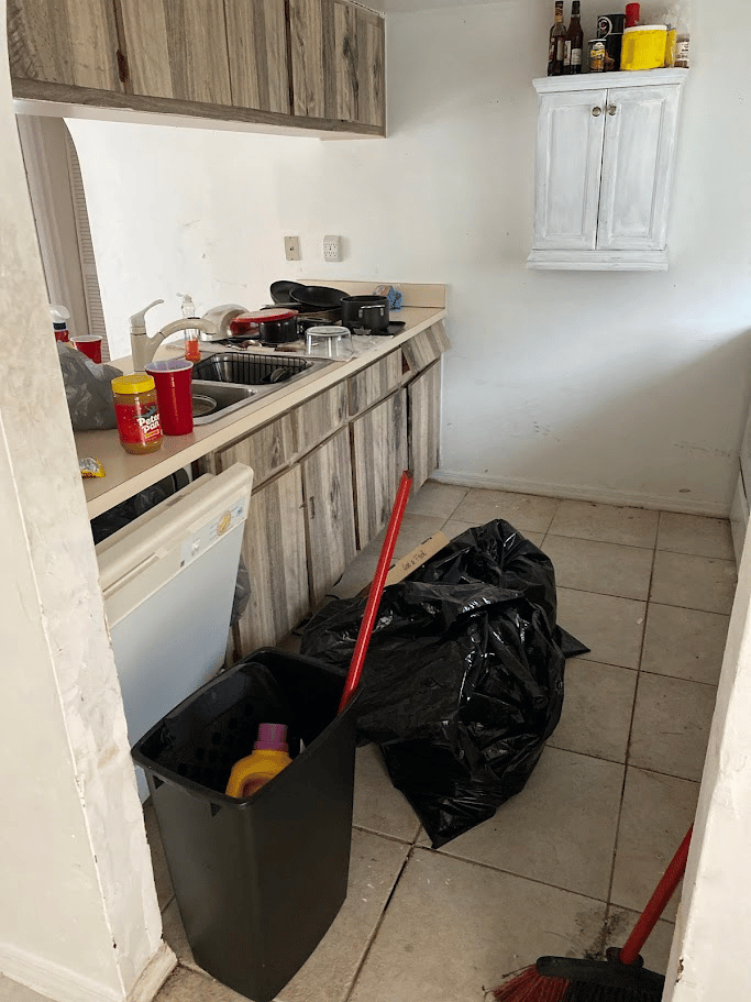 Kitchen with trash bags, dirty dishes, and clutter before professional junk removal