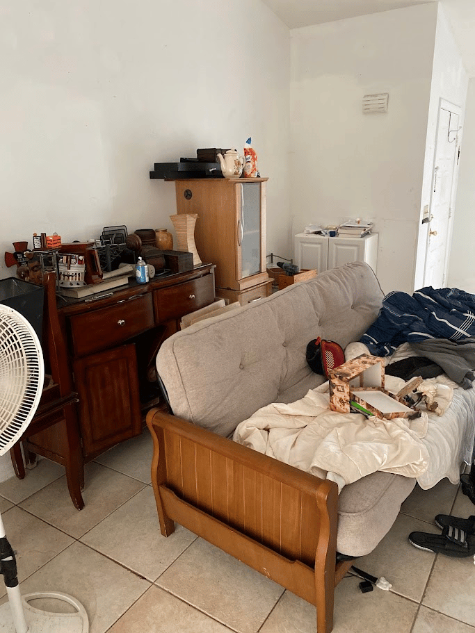 Living room filled with furniture, clothing, and personal items before junk removal