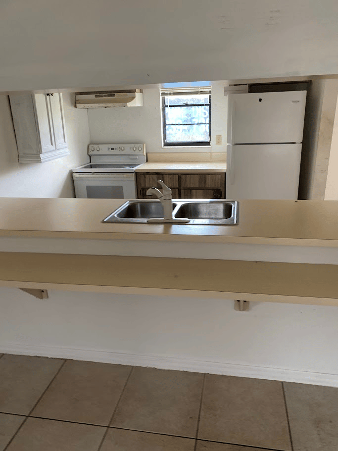 Cleared kitchen with sink, stove, and refrigerator visible