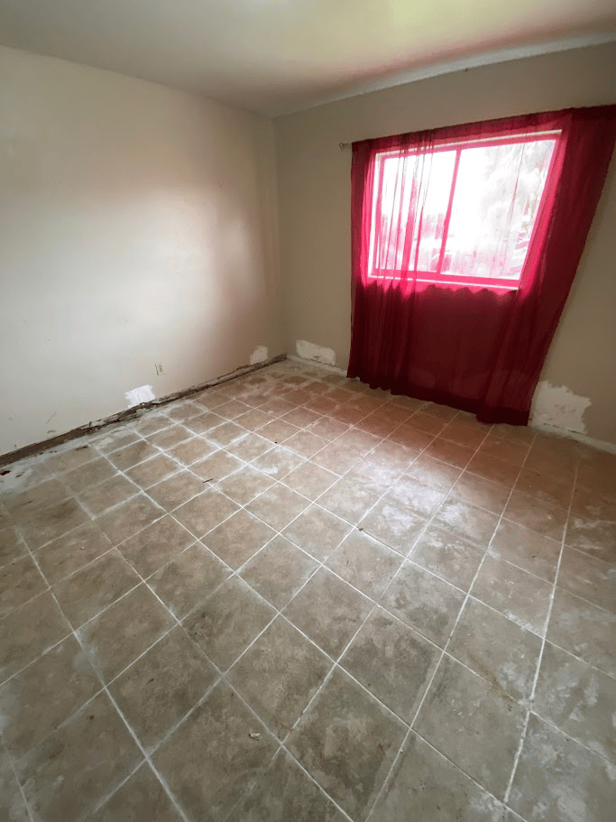 Empty room with tiled floor and patched wall areas