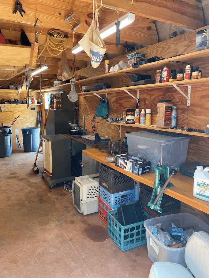 Garage workshop with neatly arranged tools, shelves, bins, and work surfaces after cleanout