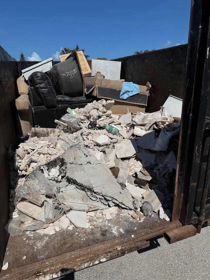 Construction debris and concrete junk removal loaded into dumpster by Pure Disposal