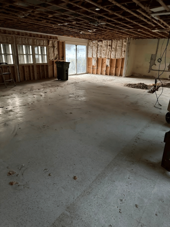Interior demolition cleanup showing exposed framing and cleared concrete floor by Pure Disposal