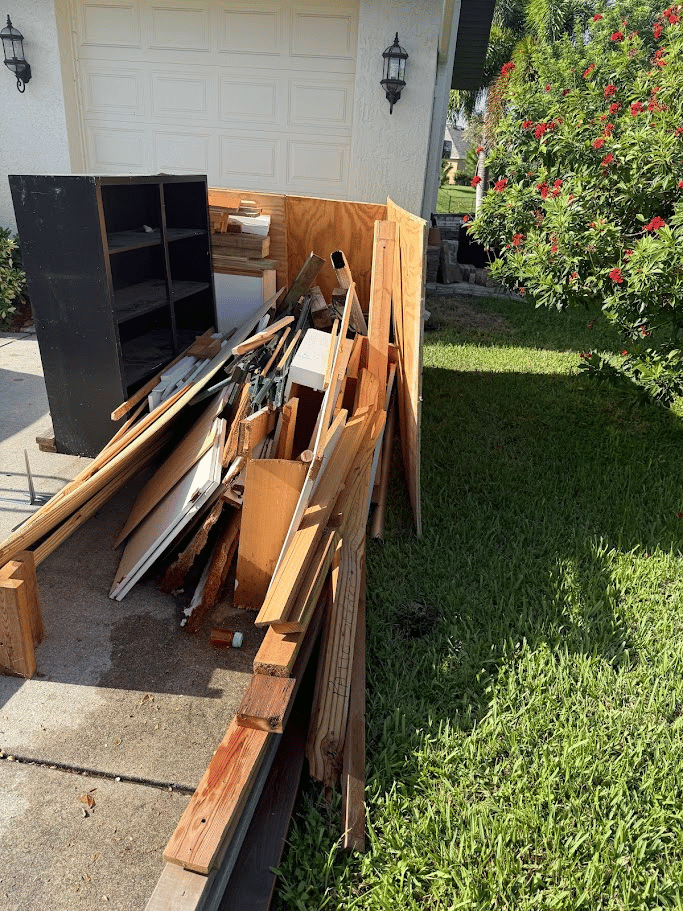 Wood debris and renovation junk stacked on driveway for removal by Pure Disposal