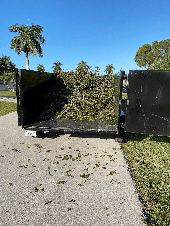 Utility trailer filled with tree branches and yard debris after outdoor cleanup